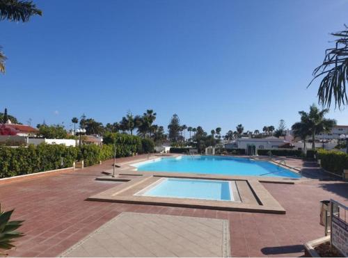 una gran piscina en una pasarela de ladrillo junto a un complejo en Villa Solycan 15, en Playa del Inglés