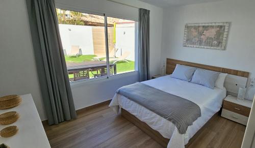 a bedroom with a bed and a large window at Villa Solycan 15 in Playa del Ingles