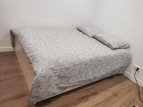 - un lit avec une couverture grise dans l'établissement Maison plein pied à Livry G., à Livry-Gargan