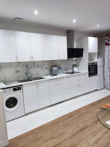 une cuisine avec des armoires blanches et une machine à laver dans l'établissement Maison plein pied à Livry G., à Livry-Gargan