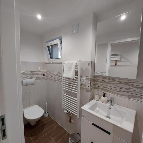 a white bathroom with a sink and a toilet at Apartmán Milan in Česká Třebová