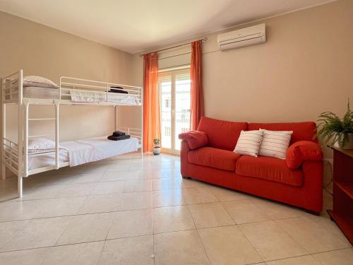 a living room with a red couch and a bunk bed at Beach House Roccalumera in Roccalumera
