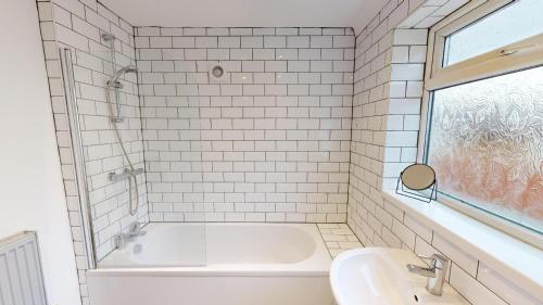 uma casa de banho em azulejos brancos com uma banheira e um lavatório. em Stunning City Centre 2024 Refurb em Sunderland