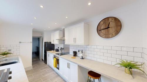 a kitchen with white cabinets and a clock on the wall at Central Stunning 3-Bed House - Free Parking in Sunderland
