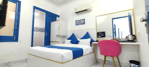 1 dormitorio con 1 cama y 1 silla rosa en The Host en Amritsar