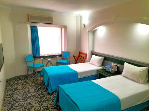 ウシャクにあるTurk Inn Uzcan Hotelのベッド2台、テーブルと椅子が備わるホテルルームです。
