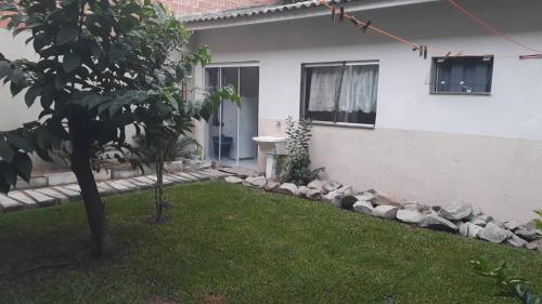 a yard of a house with a tree and a building at Ambiente acolhedor com jardim para pets in Matinhos