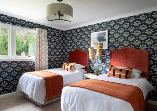 two beds in a room with blue wallpaper at Overthickside Cottage in Jedburgh