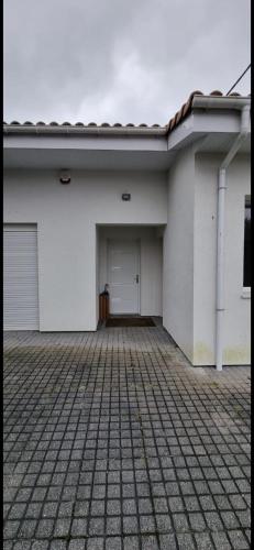 a white building with a garage and a door at Belle chambre privée avec douche et toilette indépendantes dans une magnifique villa in Andernos-les-Bains