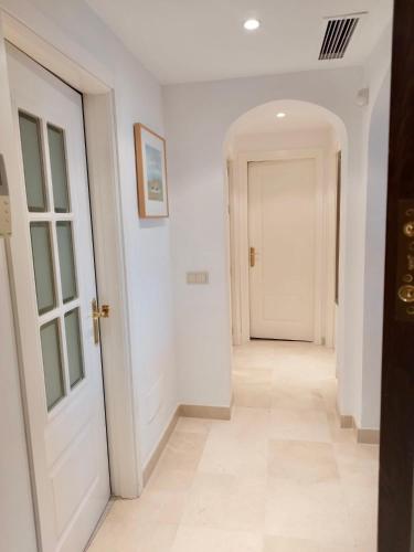 a hallway with white walls and a white door at Los Arqueros Las Jacarandas in Benahavís