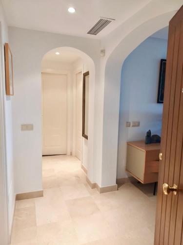 a hallway with white walls and a wooden door at Los Arqueros Las Jacarandas in Benahavís