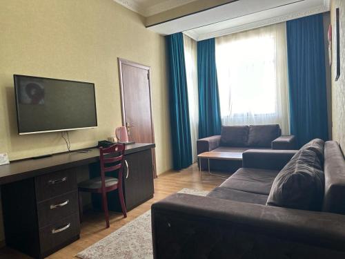 a living room with a couch and a tv at Sherlock Hotel Baku in Baku