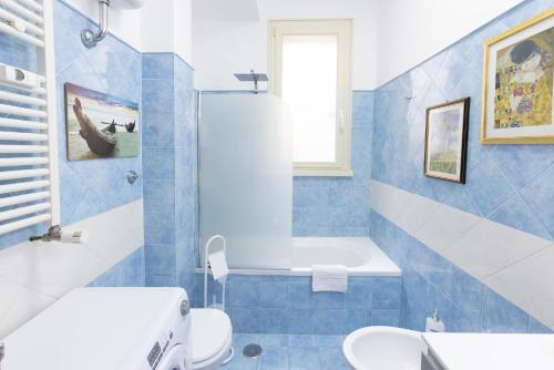 La salle de bains bleue et blanche est pourvue d'une baignoire et de toilettes. dans l'établissement Baglioni Vatican House, à Rome