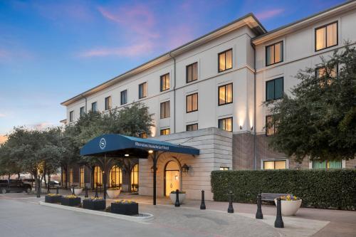 a large white building with a blue canopy in front of it at Sheraton Hotel Stonebriar in The Colony