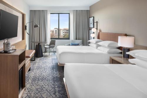 ザ・コロニーにあるSheraton Hotel Stonebriarのベッド2台、薄型テレビが備わるホテルルームです。
