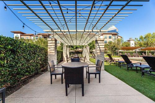 a patio with a table and chairs under a pergola at Sheraton Hotel Stonebriar in The Colony