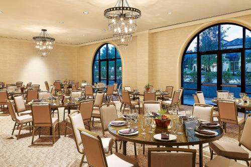 a dining room with tables and chairs and large windows at Sheraton Hotel Stonebriar in The Colony