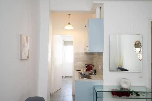 a kitchen with white cabinets and a glass table at My White Studio Mykono Town in Mikonos