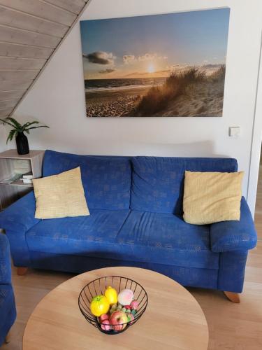 a blue couch with a bowl of fruit on a table at Silbersee90 in Frielendorf