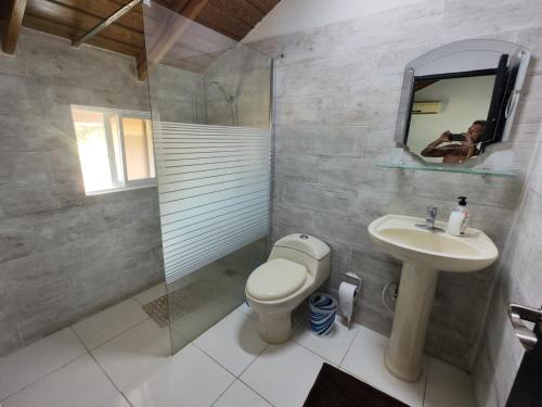 y baño con aseo, lavabo y espejo. en Las Pascualas Samana Condo Townhouse, en Santa Bárbara de Samaná