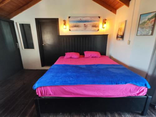 1 dormitorio con 1 cama grande con sábanas rosas y azules en Las Pascualas Samana Condo Townhouse, en Santa Bárbara de Samaná