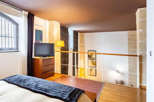 1 dormitorio con 1 cama y TV en artQhost Jerez Huge Loft & Free Parking, en Jerez de la Frontera