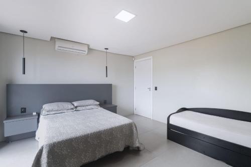 um quarto branco com uma cama e uma parede branca em Jarda Beach House 50mts do mar na praia Itapeva sul Torres RS em Torres