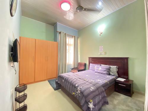 Bays Villa في Koforidua: غرفة نوم فيها سرير وكرسي