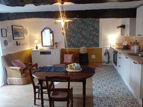 une cuisine avec une table et des chaises dans une pièce dans l'établissement Maison de charme : Ti Pauline., à Dinan