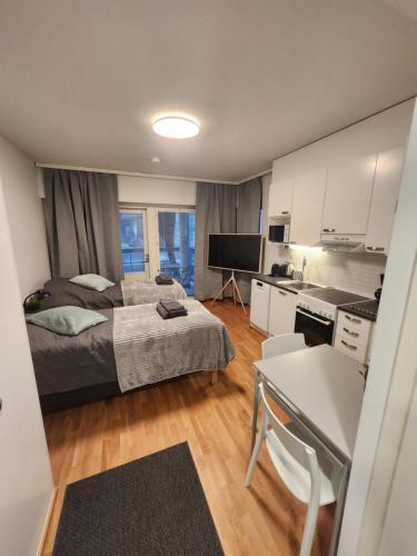 a small bedroom with a bed and a kitchen at Viihtyisä täysin kalustettu ja varustettu yksiö Logomolla 1vrk-36kk in Turku