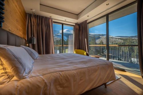 a bedroom with a large bed and a large window at DAMIAN JASNA HOTEL RESORT and RESIDENCES in Demanovska Dolina