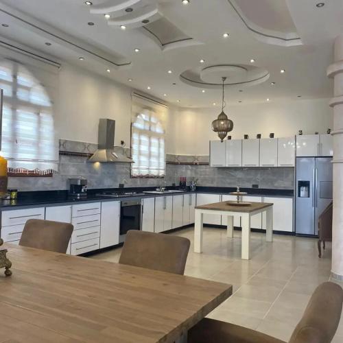 a large kitchen with white cabinets and a wooden table at Maison d'Hôte - Le Beau Panorama in Berkawe