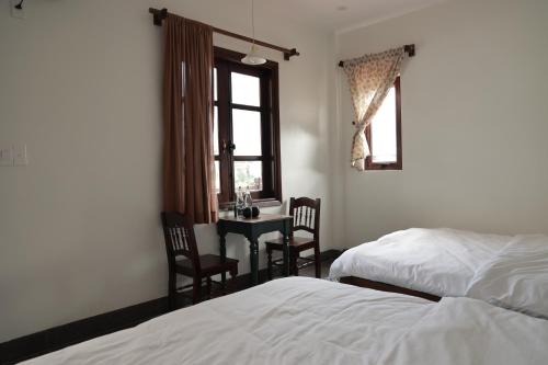a bedroom with a bed and a desk and a window at Anio Ha Giang Hotel in Ha Giang