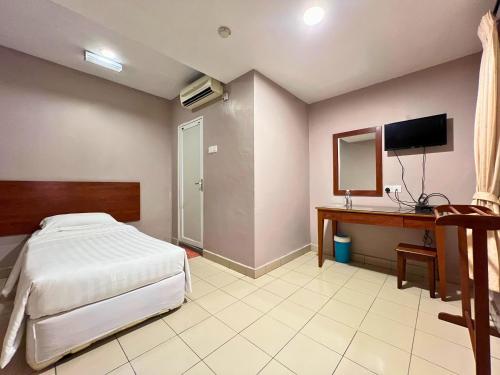 a bedroom with a bed and a desk and a television at Tropicana Hotel in Gemas