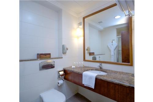 SAJA Hotels Makkah في Al Masfalah: حمام مع حوض ومرآة ومرحاض