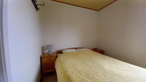 een slaapkamer met een bed met een gele sprei en een lamp bij Vakantiewoning Ter Streep in Middelkerke