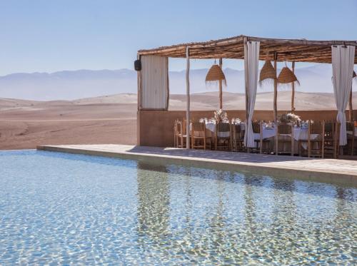 um restaurante com mesas e cadeiras ao lado de uma piscina de água em Les Terrasses d'Agafay em El Karia