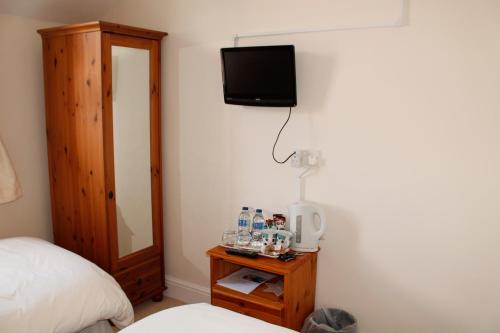 a bedroom with a bed and a television on the wall at Pebbles House in Seaton