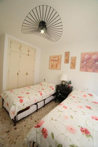 Un dormitorio con dos camas y un ventilador. en Luchana 15, en Málaga
