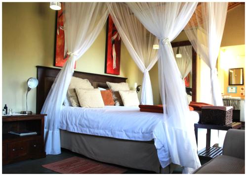 a bedroom with a canopy bed with white drapes at Blyde Mountain Country House in Hoedspruit