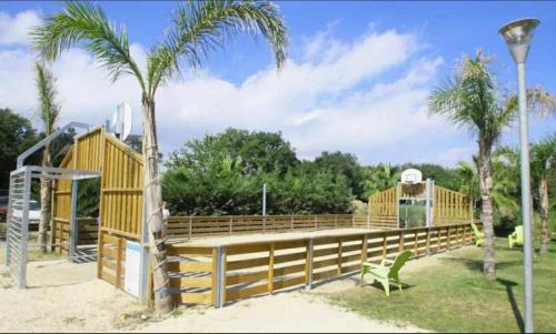a wooden playground with a slide and palm trees at Camping le clos du thym - Argelès-sur-Mer in Argelès-sur-Mer