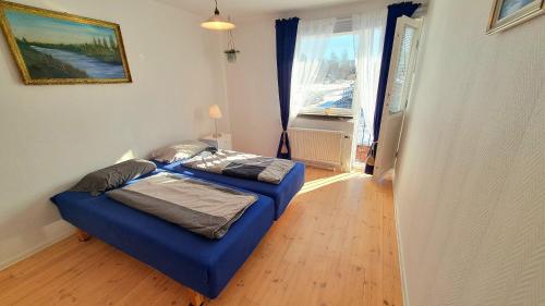 Smålands gemütliche Apartments direkt am Fluss في Högsby: غرفة نوم بسرير ازرق في غرفة مع نافذة