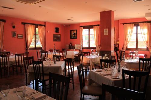 a restaurant with tables and chairs in a room with red walls at Hotel Rural Carlos I in Garganta la Olla