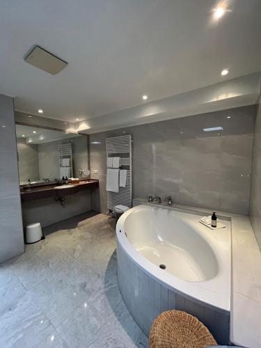 a large bathroom with a large tub and a sink at Hotel de la Gaichel in Eischen