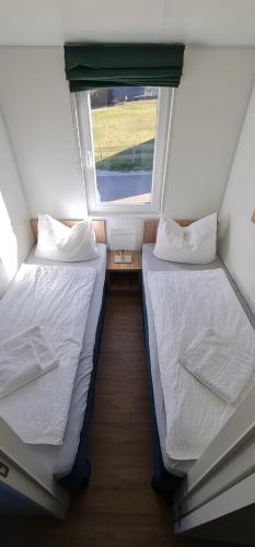 two beds in a small room with a window at Haus Ballum in Birgland