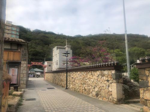 una pared de piedra junto a una calle con un edificio en Countryside B&B, en Nangan