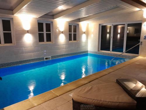 una piscina de agua azul por la noche en Pheasants Roost With Indoor Pool In Devon en Broadwoodkelly