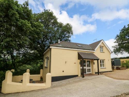 una pequeña casa blanca con una valla delante en Pheasants Roost With Indoor Pool In Devon en Broadwoodkelly