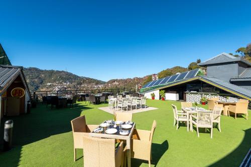 an outdoor restaurant with tables and chairs on the grass at Ramada by Wyndham Kasauli in Kasauli