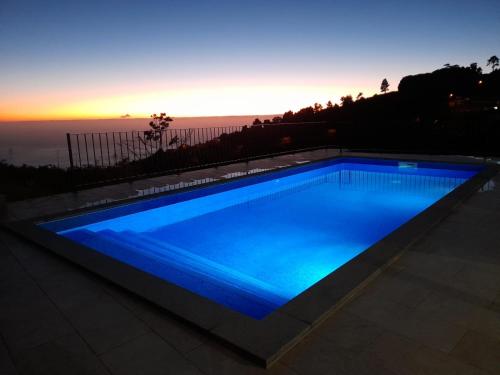 a swimming pool with blue lighting in front of the ocean at Casa dos Avós in Fajã da Ovelha